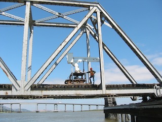 A man standing on top of a metal bridge.